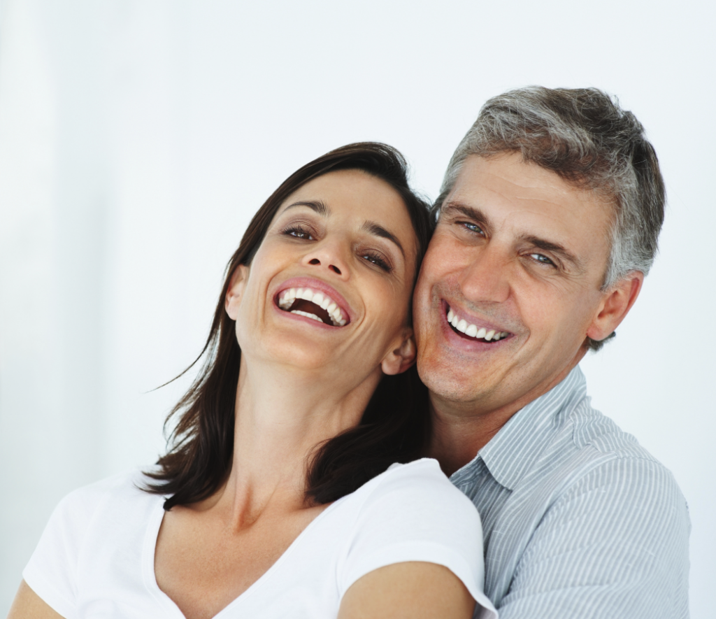 A middle-aged couple embrace and smiles confidently